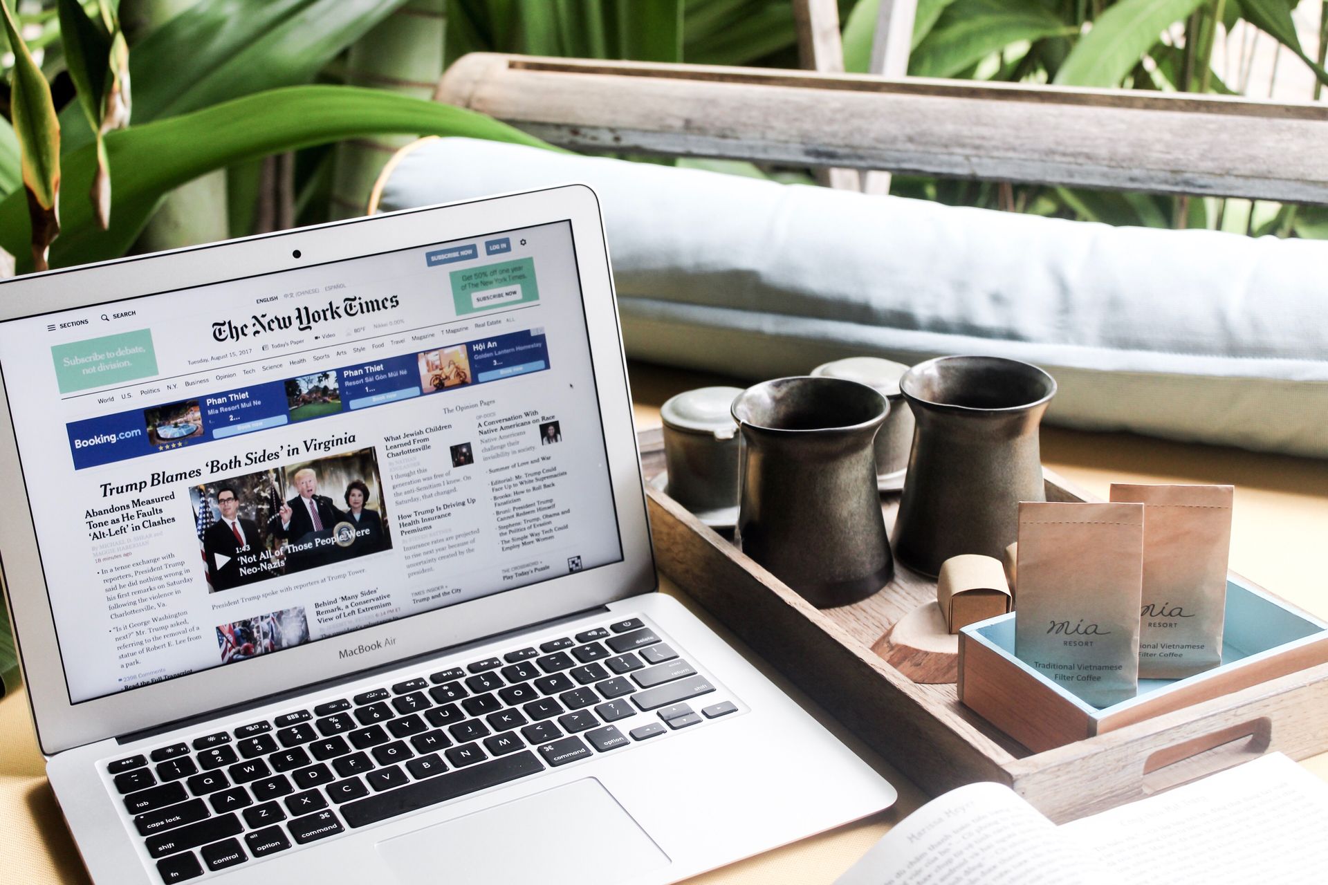High angle of modern laptop with news on screen placed on table next to tin cups