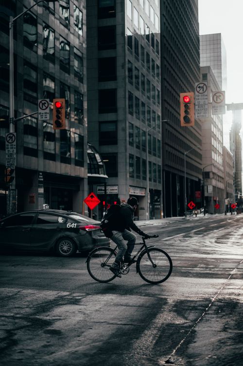 Free A cyclist rides through downtown Canada, juxtaposed with urban architecture and early morning traffic lights. Stock Photo