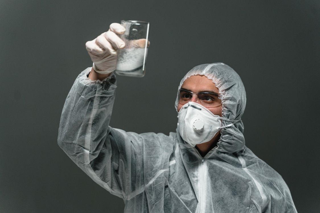 Free Scientist in full protective gear analyzing a substance in a laboratory setting. Stock Photo