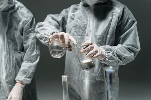 Researchers in protective suits working with beakers in a science lab.