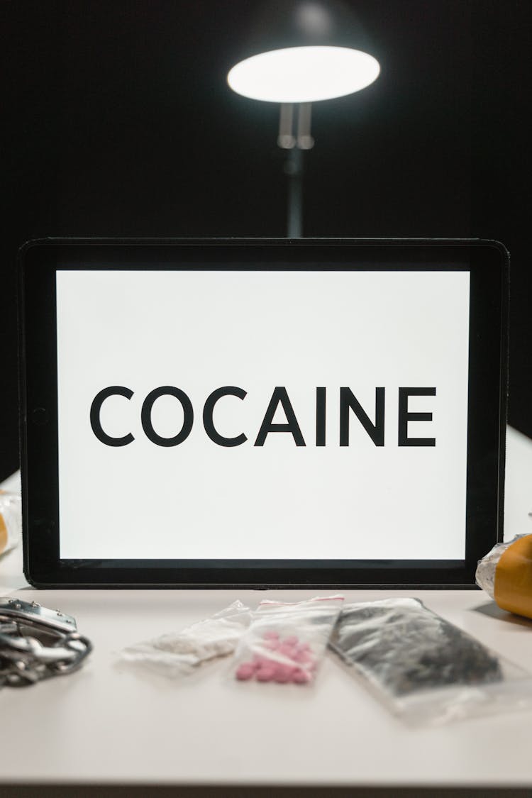 White Board With Cocaine Text And Drugs On Table