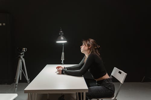 Free Woman in Black Long Sleeve Shirt Sitting in a Room for Interrogation Stock Photo