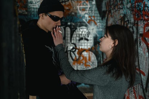 Free Man in Hoodie Jacket and Black Sunglasses Smoking Beside a Woman  Stock Photo