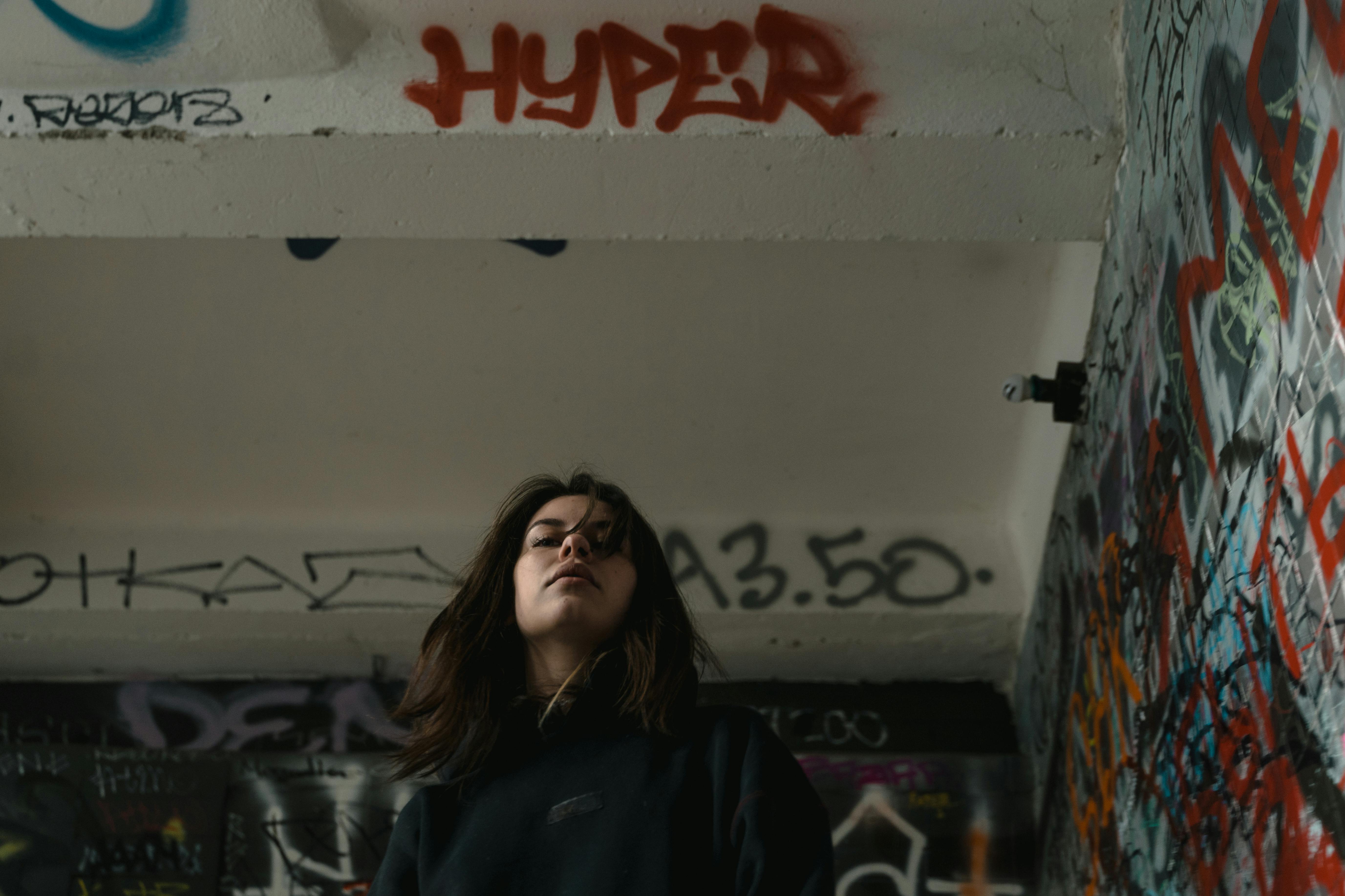 woman in black hoodie standing near white wall