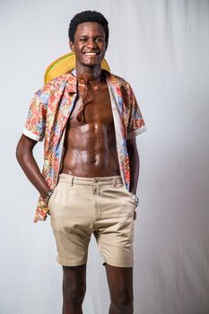 African man in colorful shirt and shorts posing with a smile in a studio setting.