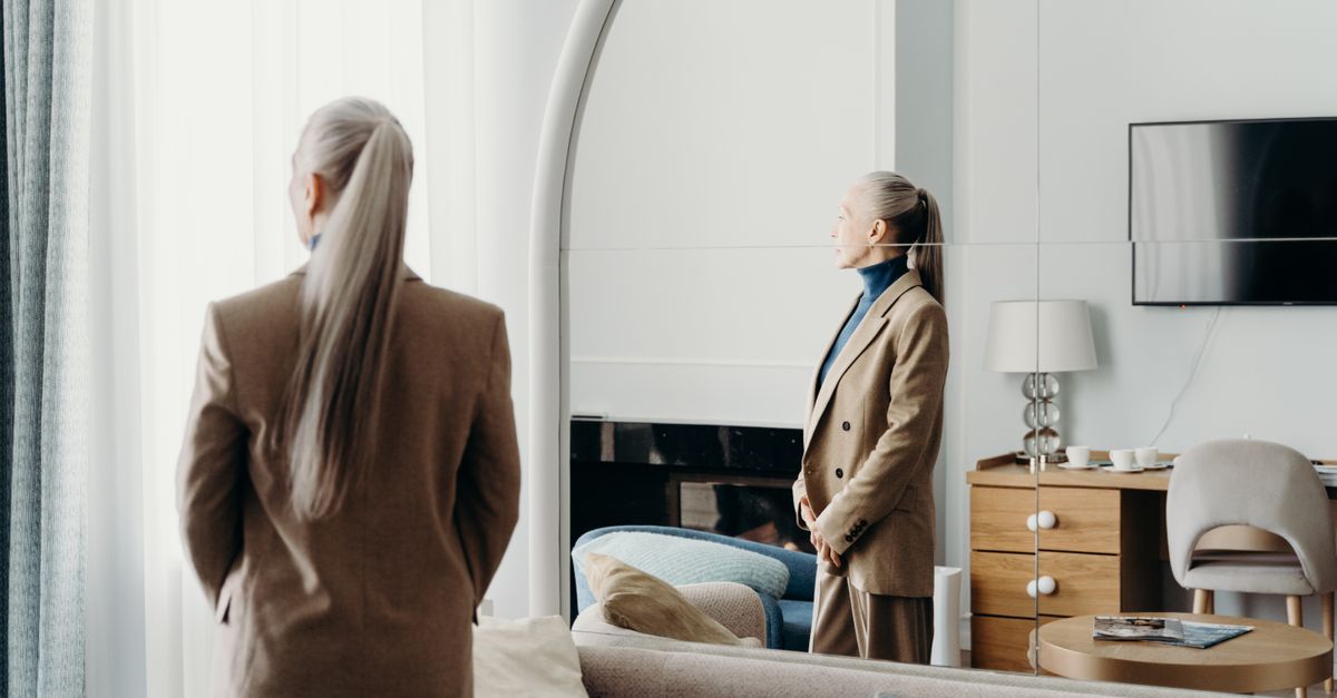 a person in a beige outfit standing in a minimalist, monochrome room