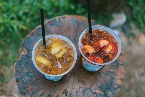 Selective Focus Photo of Two Juice Filled Plastic Cups