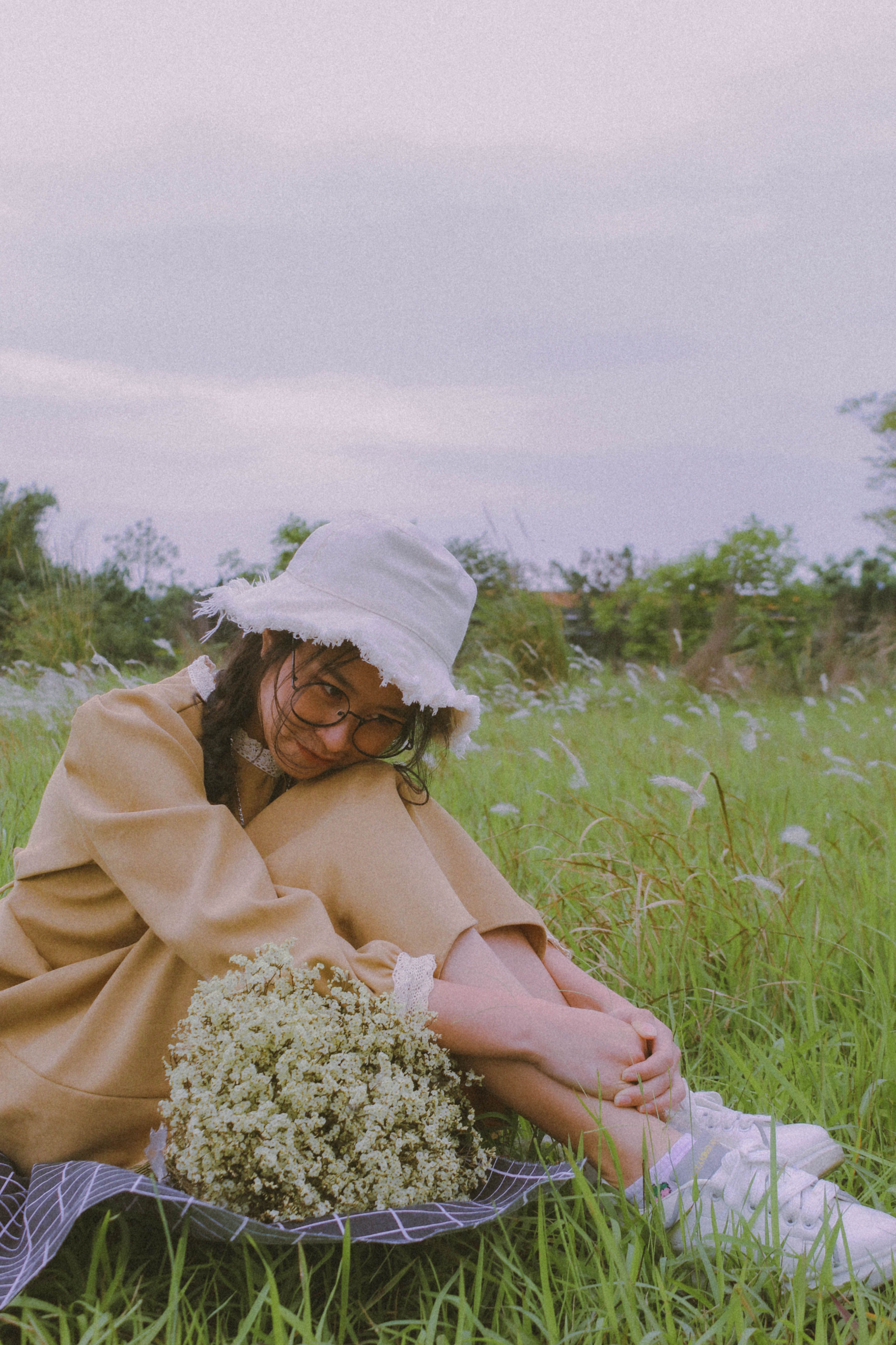 A Woman Sitting on Green Grass Beside the Bouquet of Flowers · Free ...