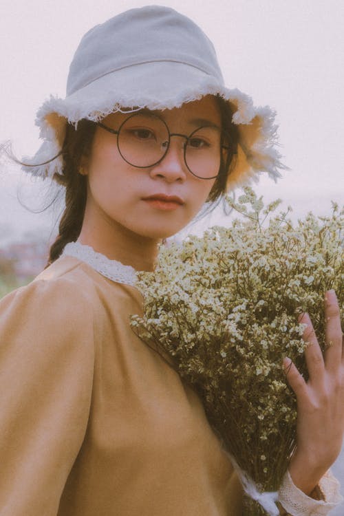 Portrait of a Girl with a White Hat Holding Flowers