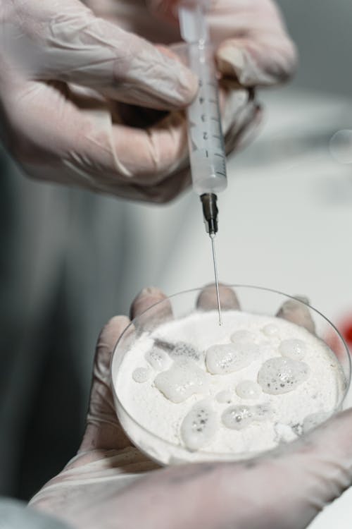 Person Holding Clear Glass Bottle With White Liquid