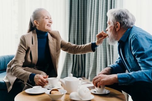 Free Senior couple smiling and sharing breakfast, creating a warm and cozy atmosphere indoors. Stock Photo