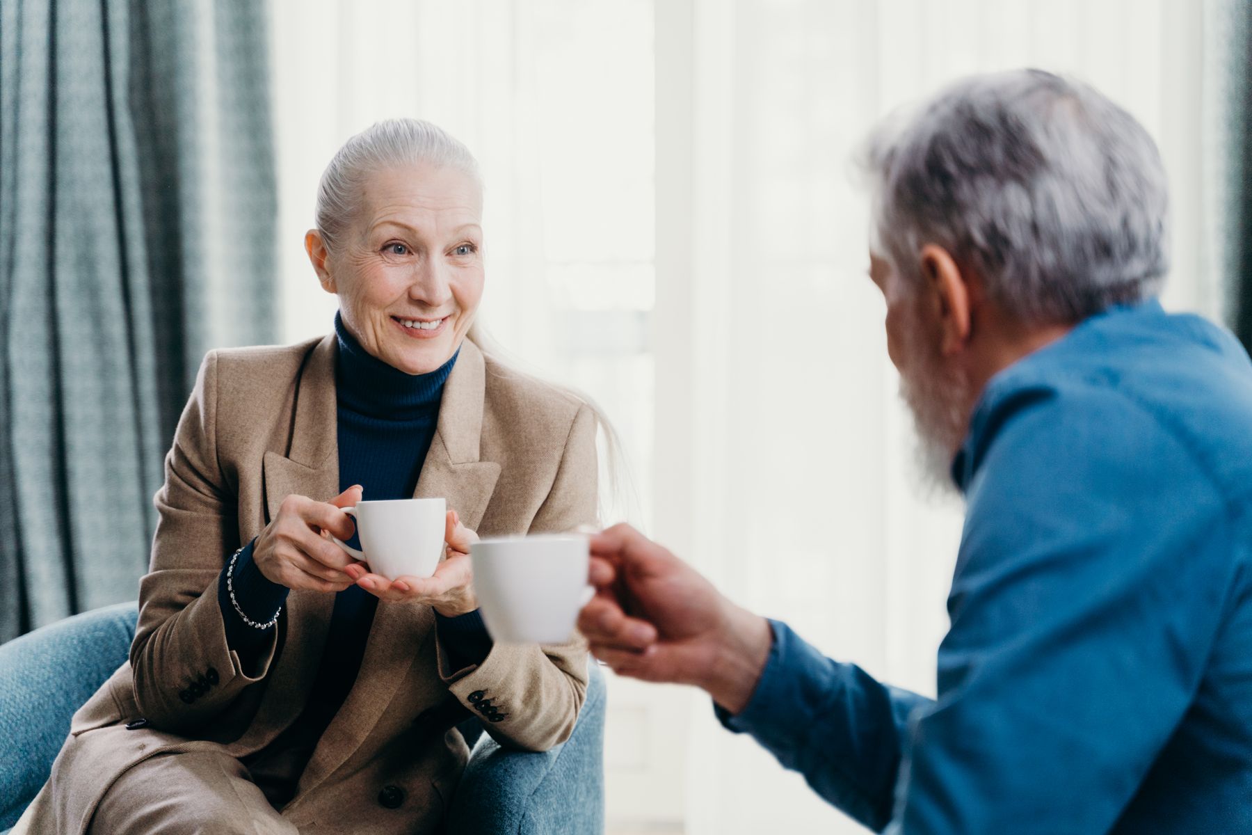 Two older adults smiling together during a relaxed coffee date
