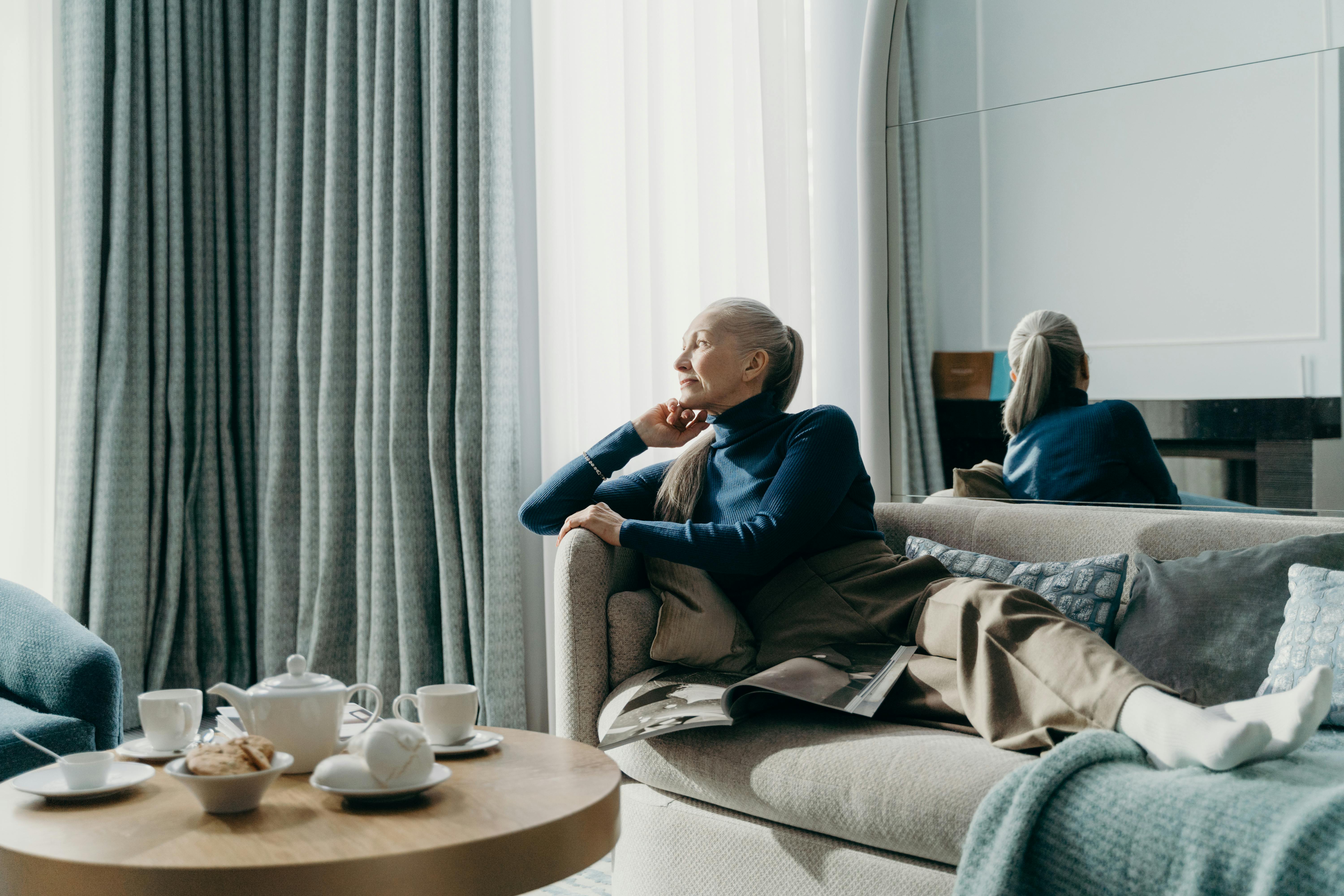 elderly woman in blue knitted sweater reclining on the couch