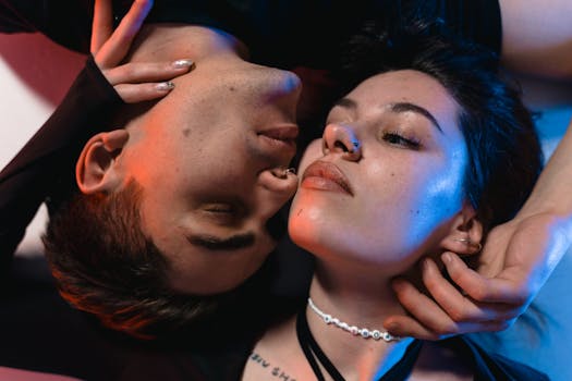 Close-up of an intimate couple under vibrant red and blue lighting, expressing connection and emotion.