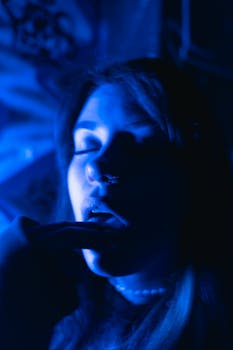 A vivid, moody portrait of a woman bathed in blue light with introspective expression.