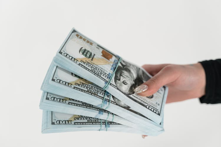 Close-Up Shot Of A Person Holding Stack Of Dollar Bills