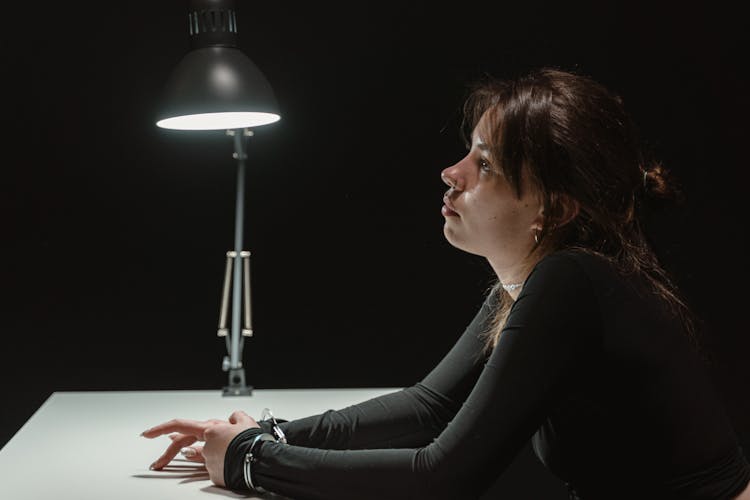 A Woman In Handcuffs Inside An Interrogation Room