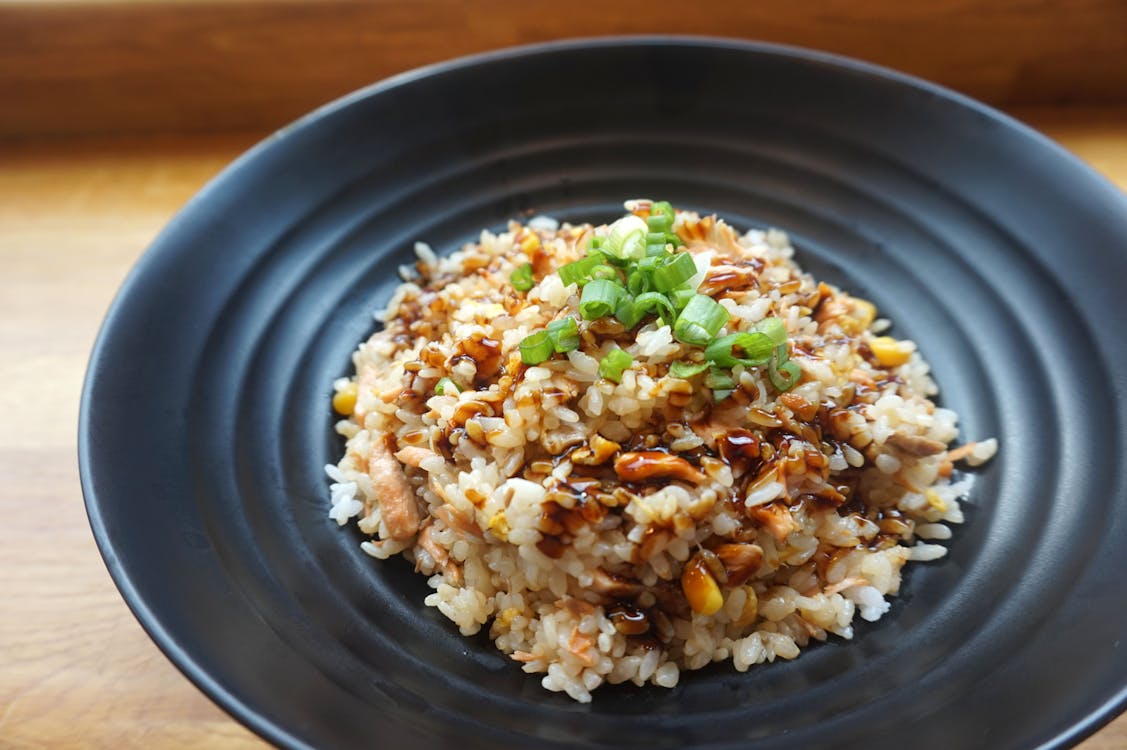 A Brown Rice Dish topped with coriander on a Black Ceramic Plate