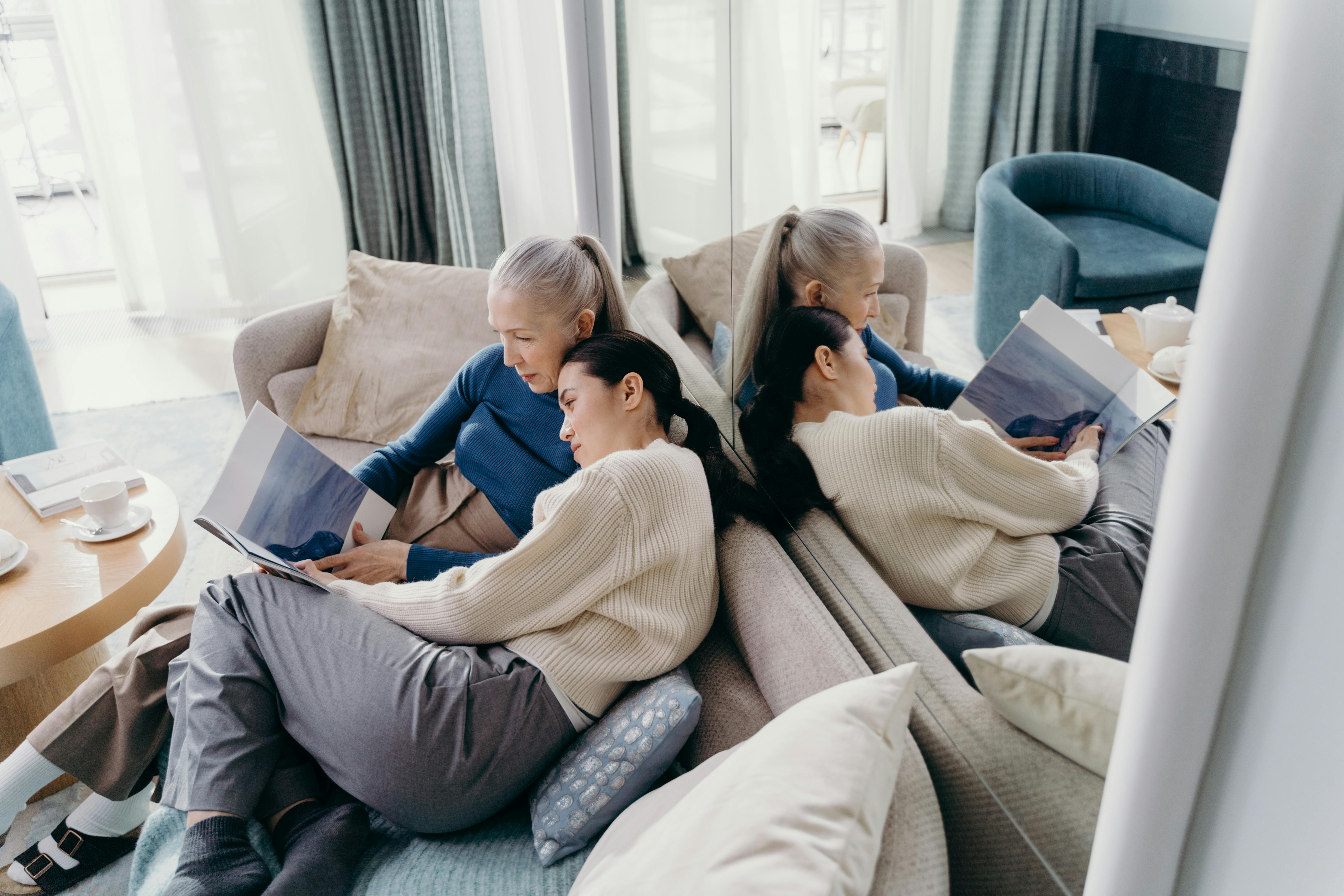 An adult daughter and her elderly mother enjoying a quiet activity together, possibly reading or knitting, with warm lighting. - mother and daughter relationship