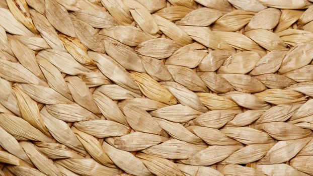 Detailed close-up of a beige woven natural fiber texture showcasing intricate patterns.