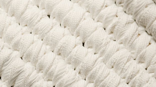 Detailed view of white knitted textile, showcasing intricate texture and pattern.