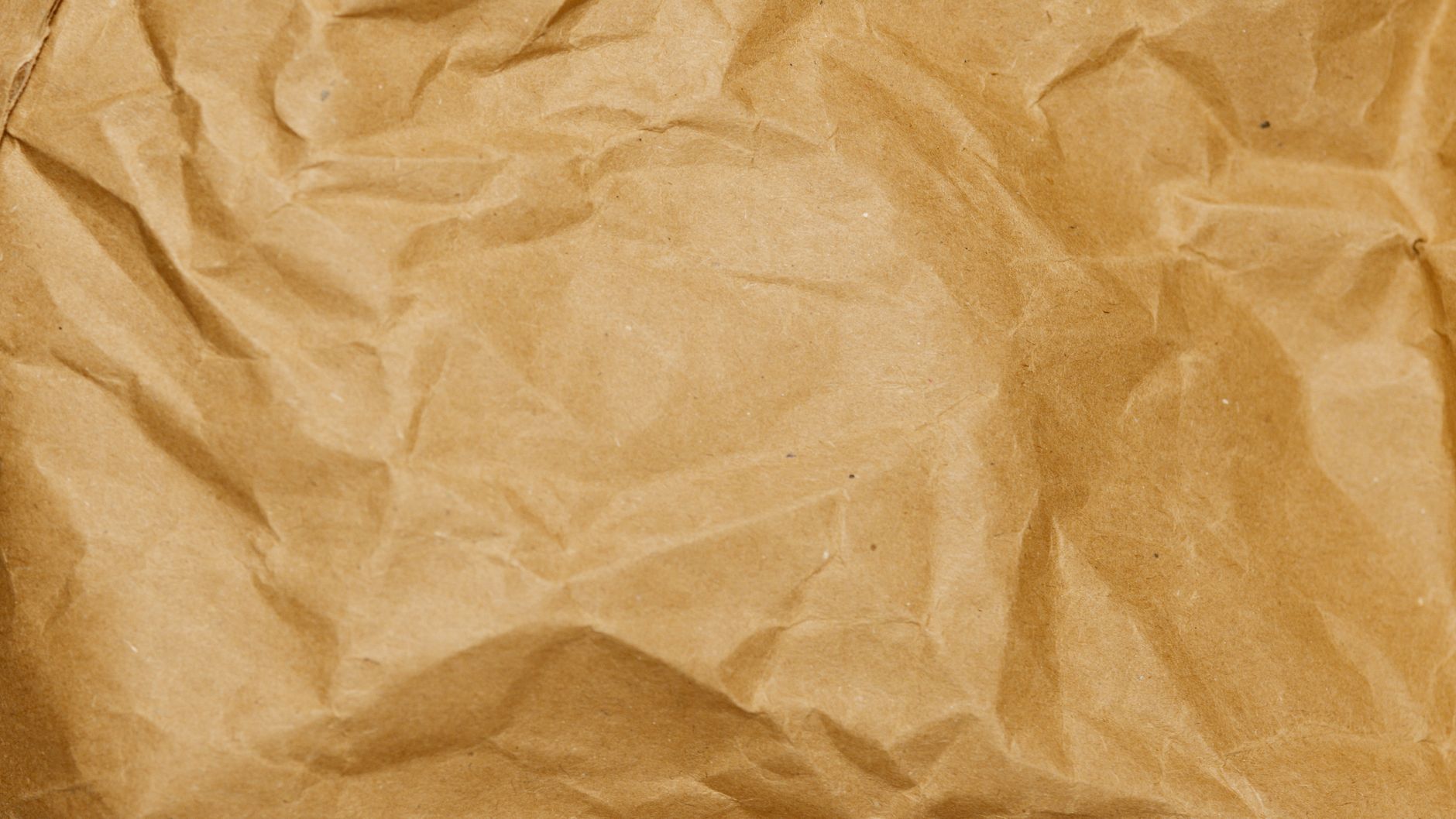 Detailed close-up of a crumpled brown paper texture showcasing folds and creases.. detailed, close, crumpled