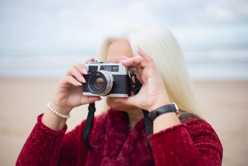 Woman in Red Sweater Taking Picture With Black and Silver Camera