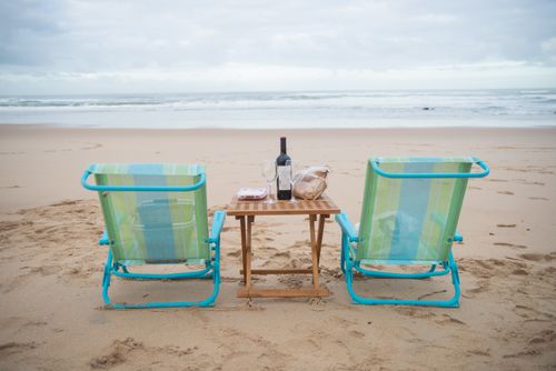 Free Tranquil beach setup with chairs and wine at Portugal's coast, perfect for relaxation. Stock Photo