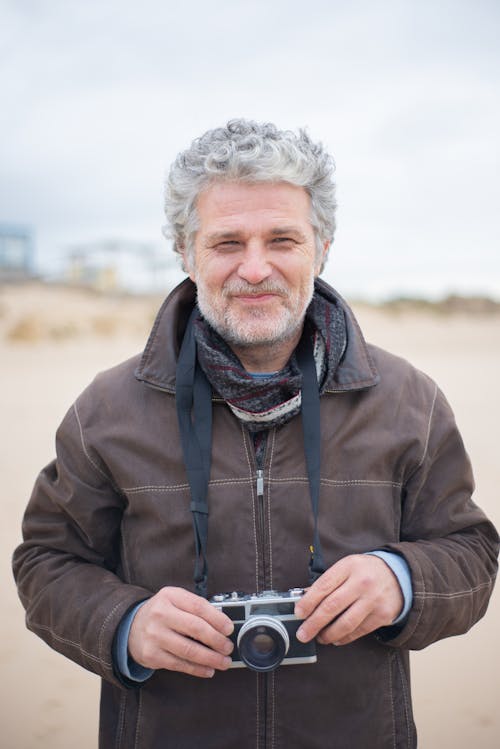 An Elderly Man with Gray Hair and Facial Hair Holding a Camera