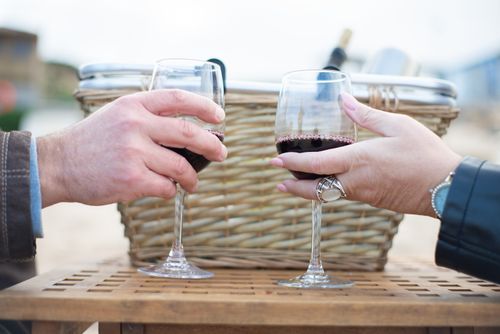 Free Two people toasting red wine glasses at an outdoor picnic scene, embodying a festive mood. Stock Photo