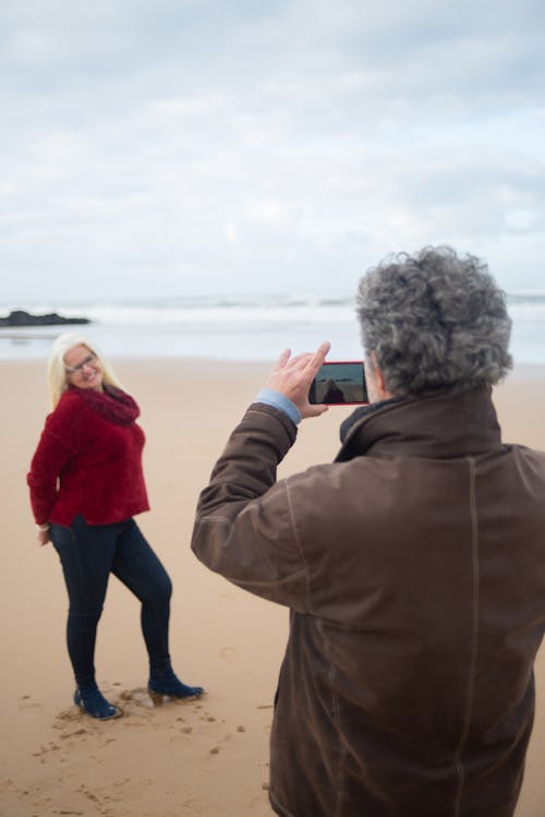 Man Taking Photo of a Woman in Red Sweater