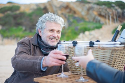 Free Elderly man with gray hair smiling while toasting wine during a beach picnic in Portugal. Stock Photo