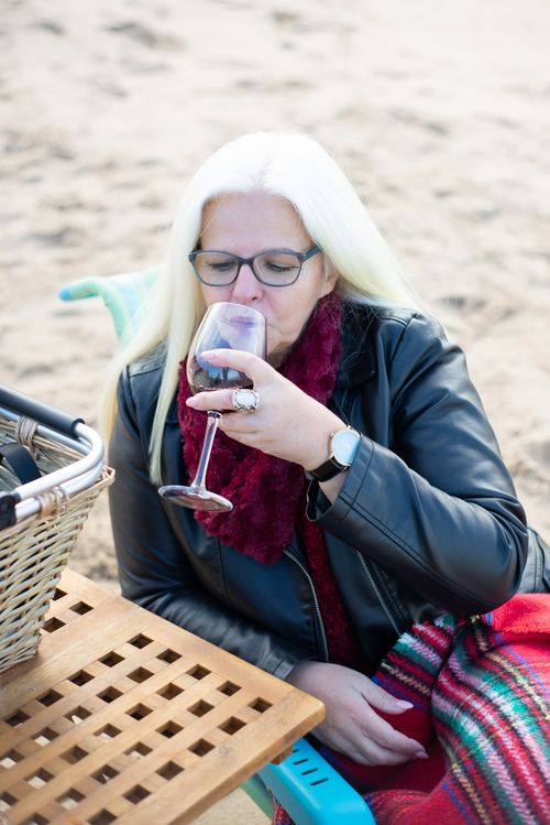 Free Serene moment of a woman sipping wine by the beach in Portugal. Stock Photo