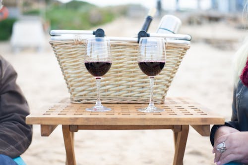 Two Glasses of Red Wine on Wooden Table Beside A Wicker Basket