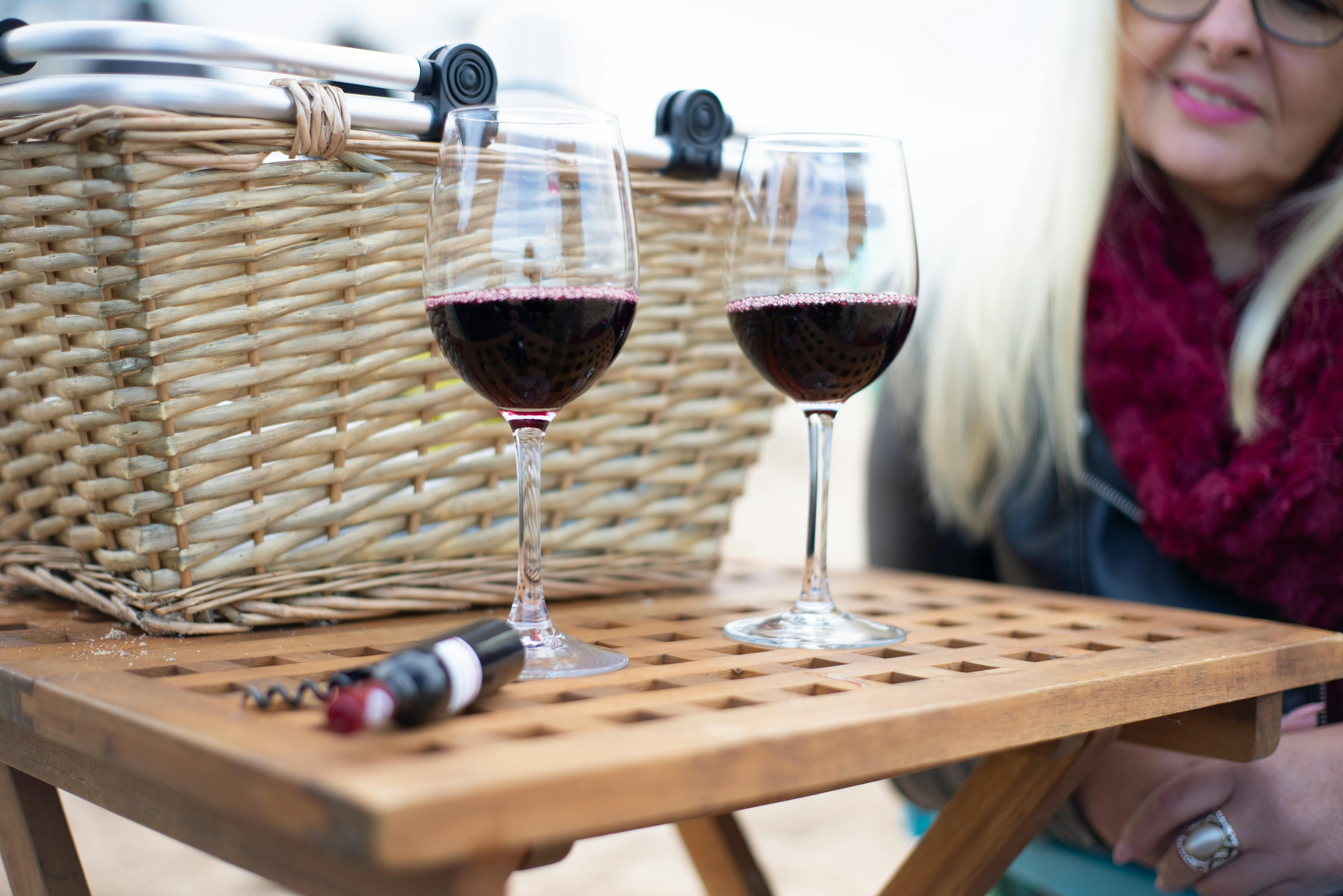 Elegant red wine glasses on a wooden table during an outdoor picnic, Portugal.