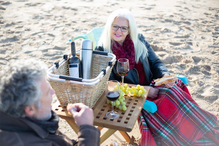 An Elderly Couple Having A Picnic By The Shore 