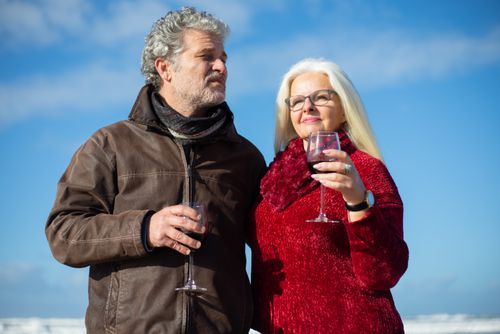 Free Elderly couple savoring red wine against a clear blue sky, enjoying togetherness and love. Stock Photo