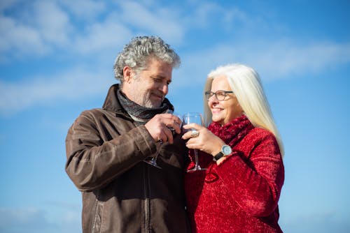 Free Elderly Couple Сlinking Glasses of Wine Under Blue Sky Stock Photo