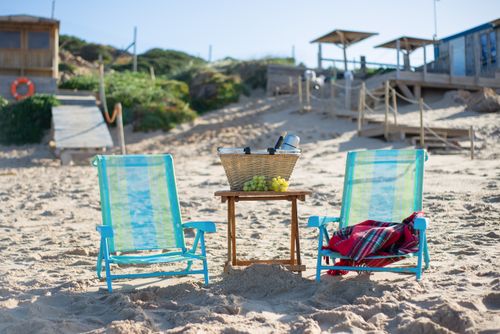 Free Serene beach setup with chairs, picnic basket, and grapes. Ideal for a relaxing seaside escape in Portugal. Stock Photo