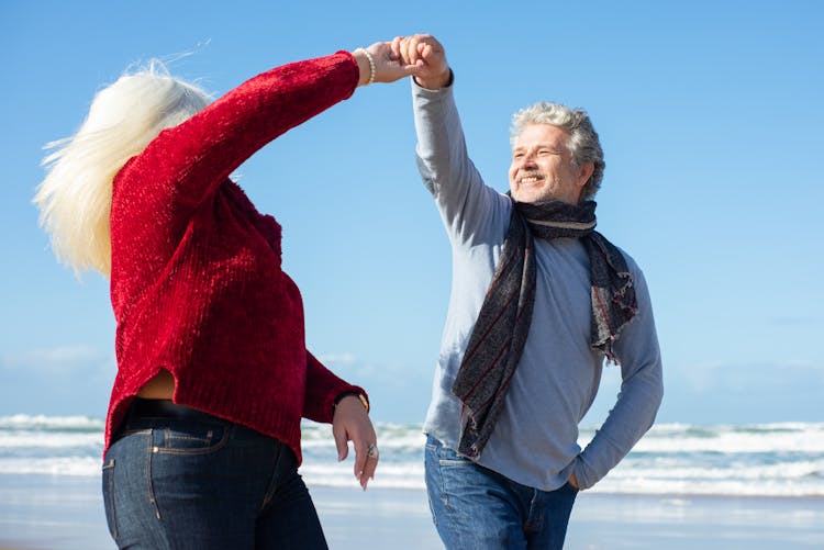 Couple Holding Hands While Walking On The Beach