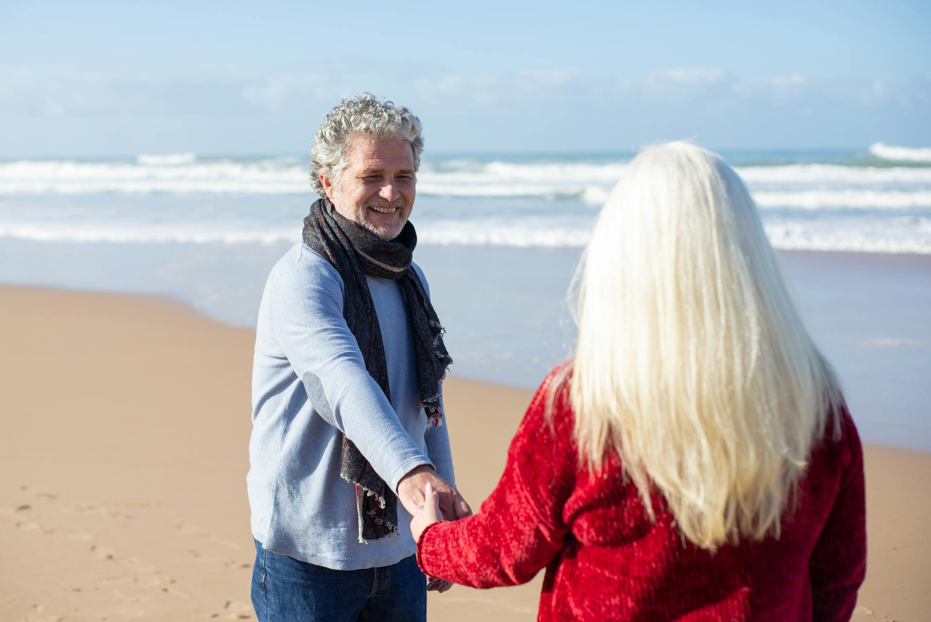 A happy senior couple holding hands and enjoying the sunny beach in Portugal.