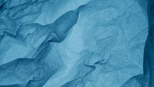 Free Abstract texture of blue crumpled paper with shadowy folds and wrinkles. Stock Photo