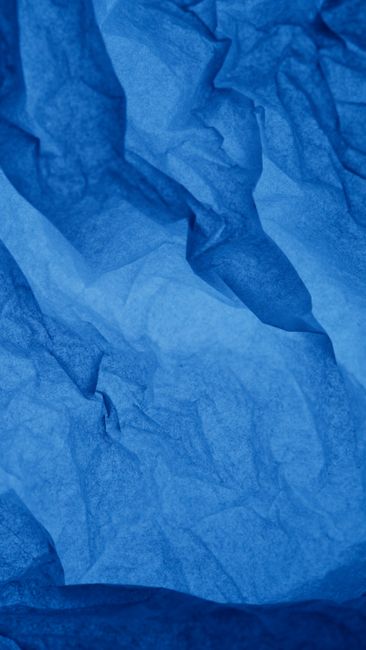 Close-up of crumpled blue paper creating a textured abstract background.