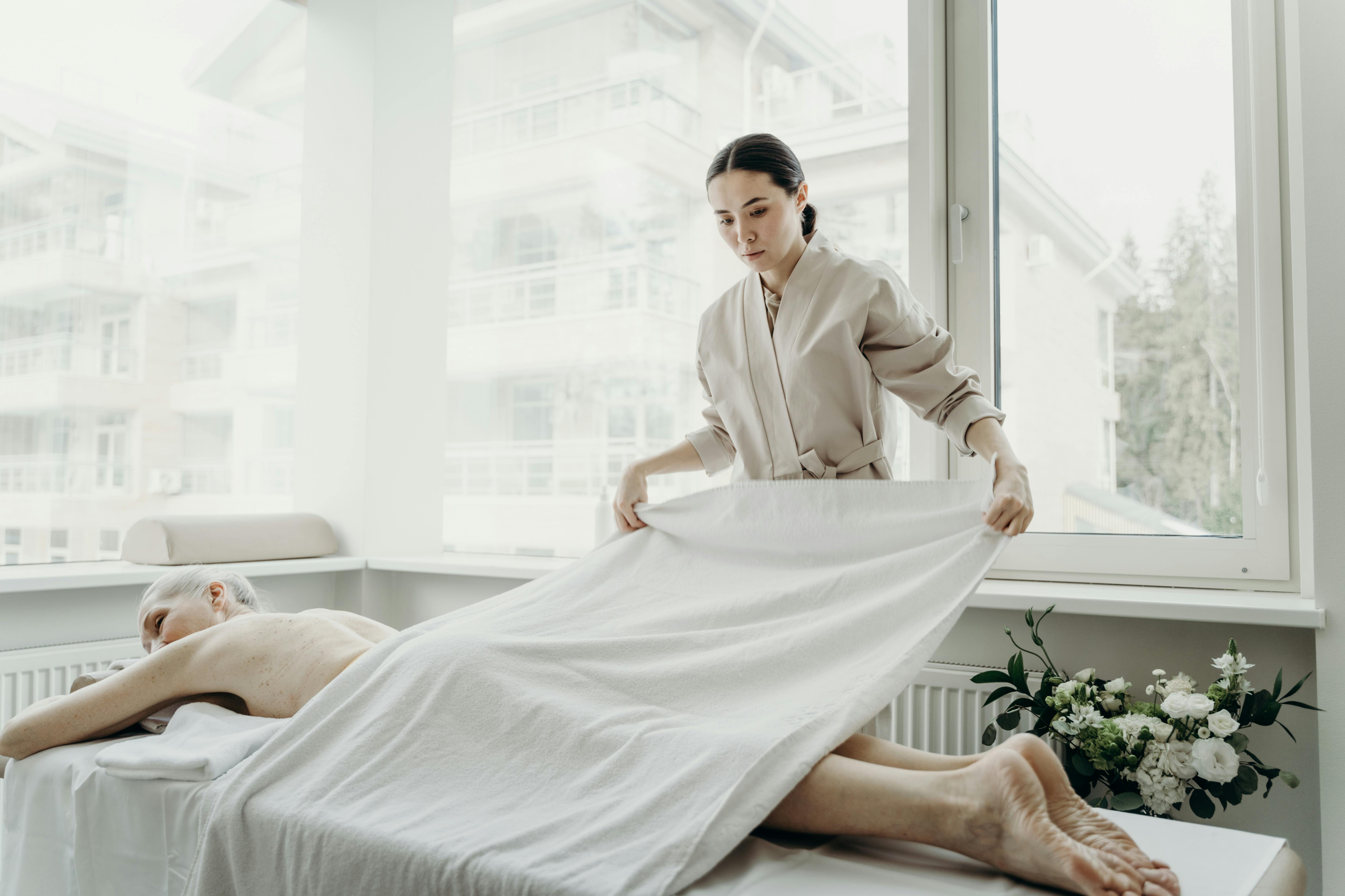 somatic massage therapy reviews Floral Park - Massage therapist providing a personalized wellness session in a modern spa setting with natural light.