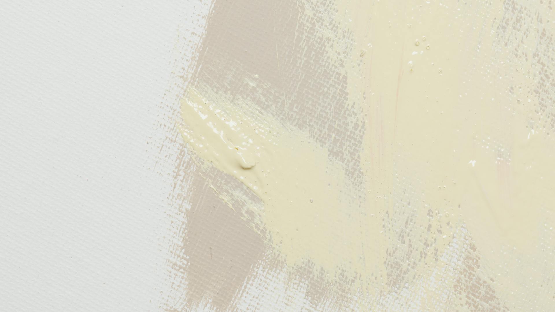 Abstract beige paint texture on canvas with soft brushstrokes.