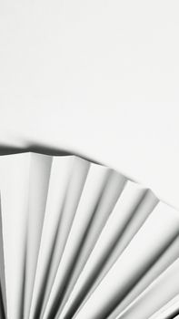 Minimalist image of folded white paper with abstract geometric design on a white background.