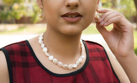 Close-up of a woman with a pearl necklace and earrings, highlighting fashion accessories.