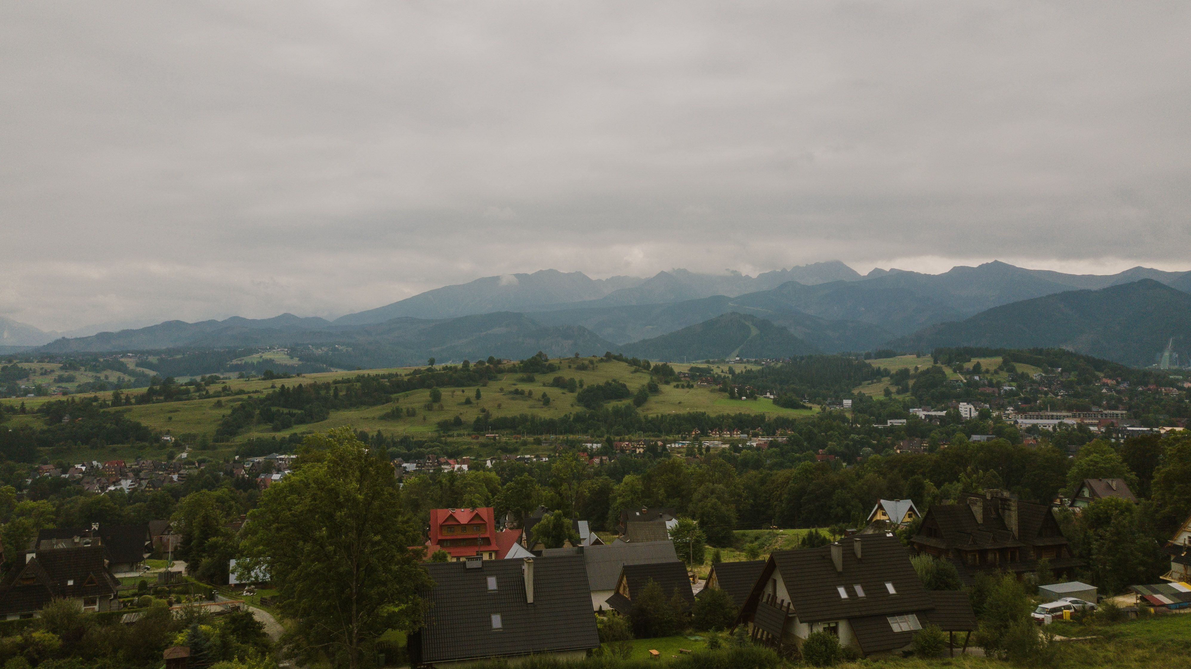Aerial view of the picturesque Tatra Mountains and surrounding Polish countryside with houses and lush greenery.