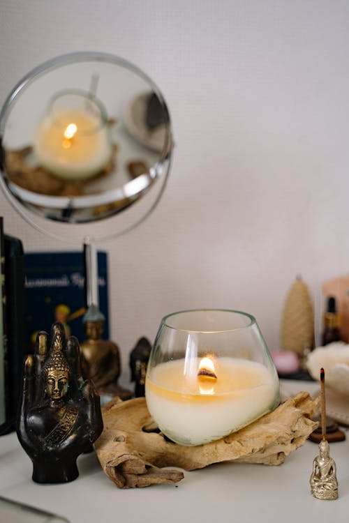 A Buddha Figurine and a Lighted Candle on a Glass Container