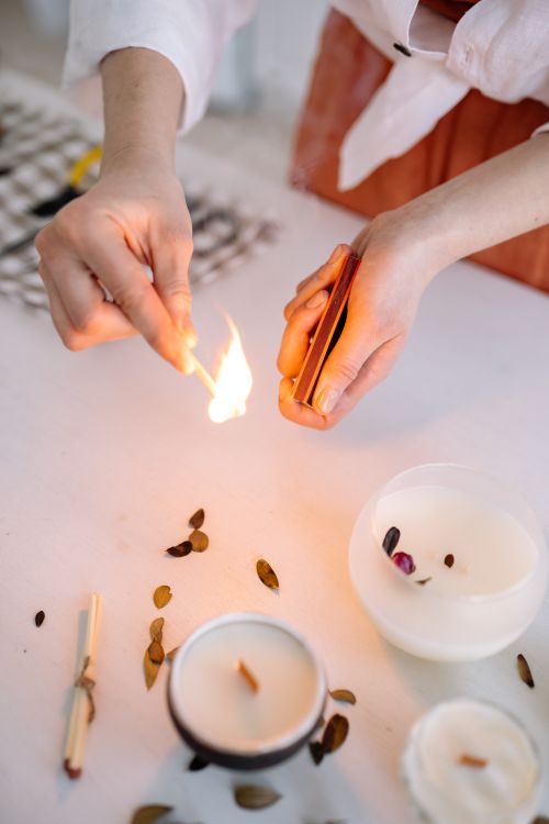 Free A close-up of hands lighting handmade candles indoors, creating a cozy atmosphere. Stock Photo